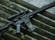 SOIDC DOC AR15 with scope leaned against wood bench